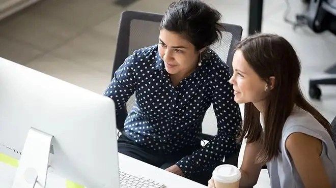 Two women working on nice systems workforce management software AI.